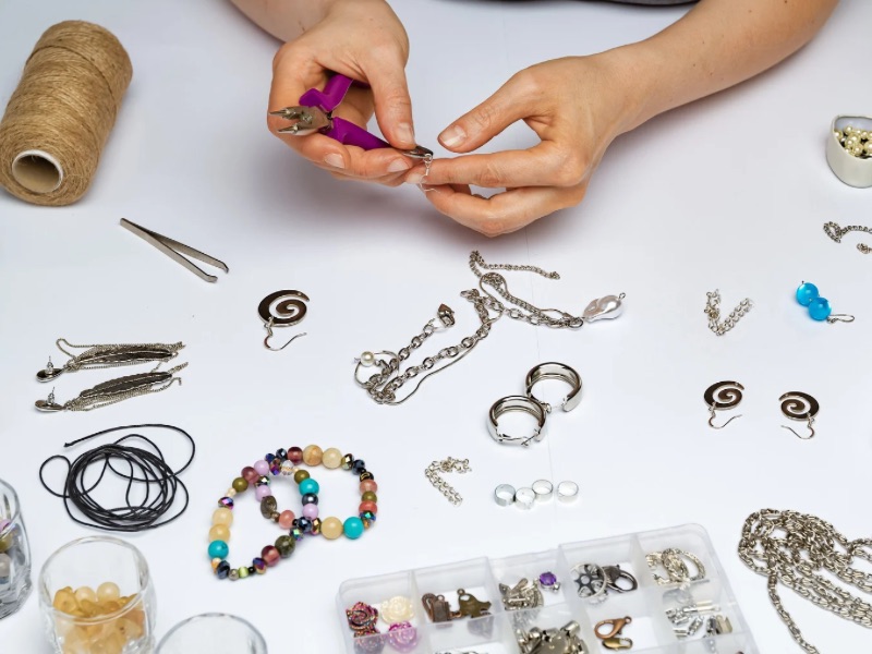 Hands setting up handmade jewelry.